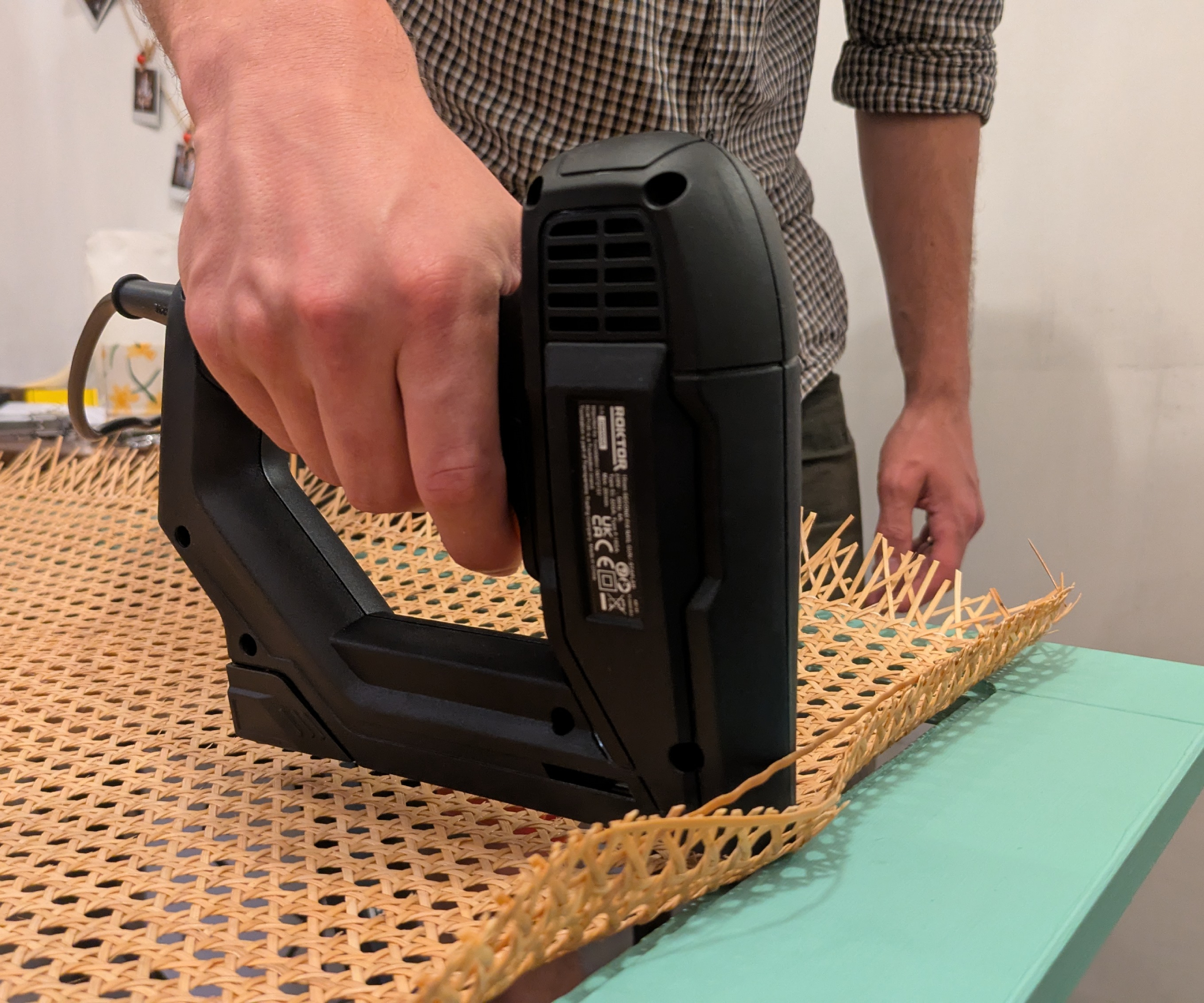 A person using a staple gun to fix cane webbing to a cupboard door