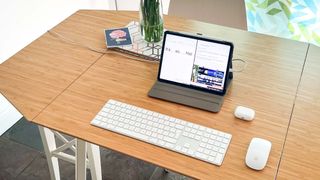 A desk set-up with an iPad Pro, Magic Keyboard, Magic Mouse 2 and AirPods Pro