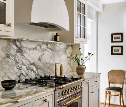 A kitchen with a veined backsplash, antique knobs and a white palette