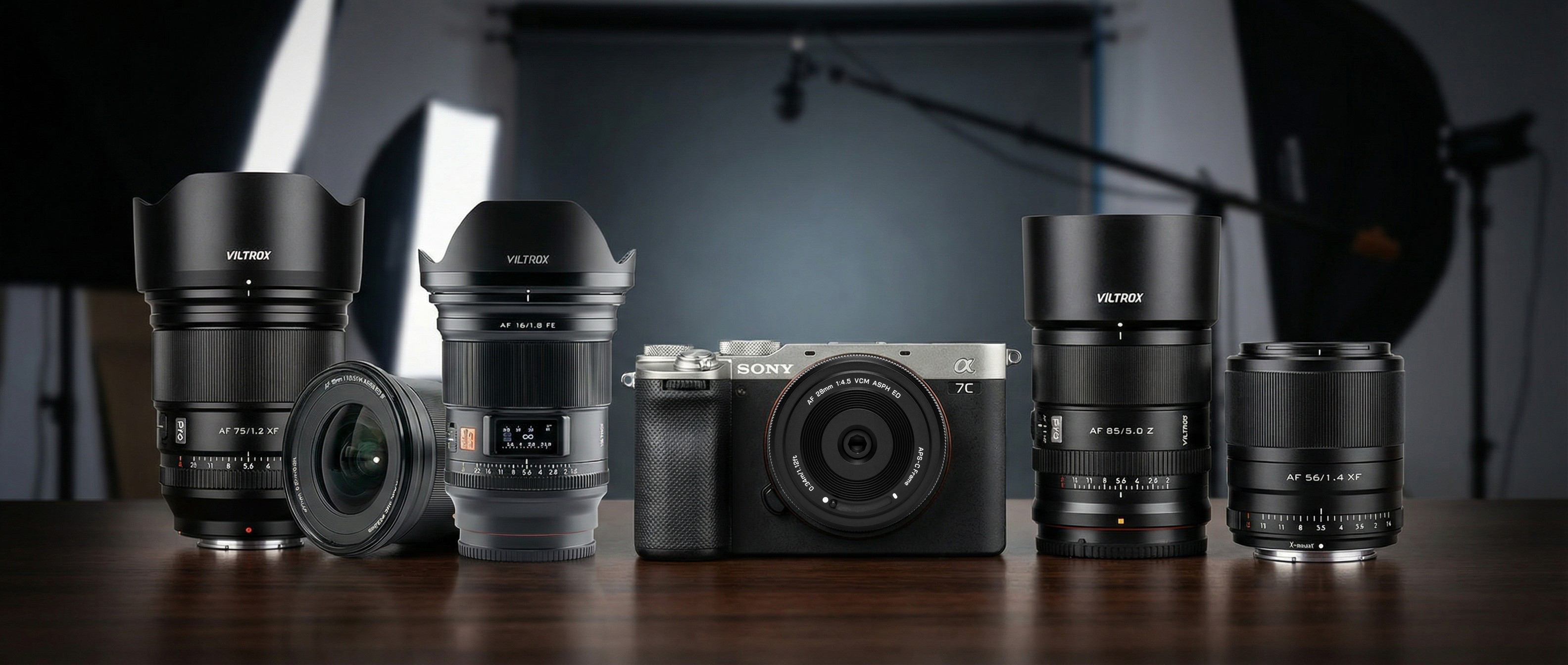 A collection of Viltrox lenses on a table in a photo studio setting, one of them is attached to a Sony A7 C. Background generated by Gemini