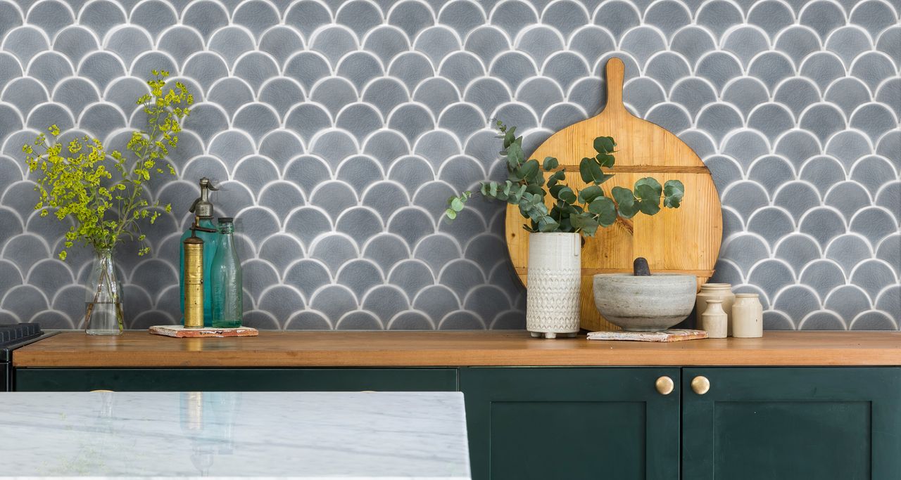 Gray scalloped kitchen wall tile ideas by Ca&#039;Pietra, with a wooden shelf, chopping board and small vases of foliage.