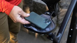 Man putting phone in Schwinn Marshall e-bike storage saddle