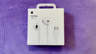 Apple USB-C EarPods in their packaging on a purple cushion