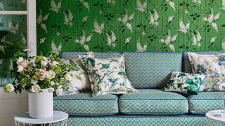 green living room with green patterned upholstered sofa and floral green wallpaper to show interior design mistakes with wallpaper measurements