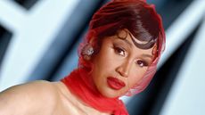 cardi b on a blue background wearing a red veil