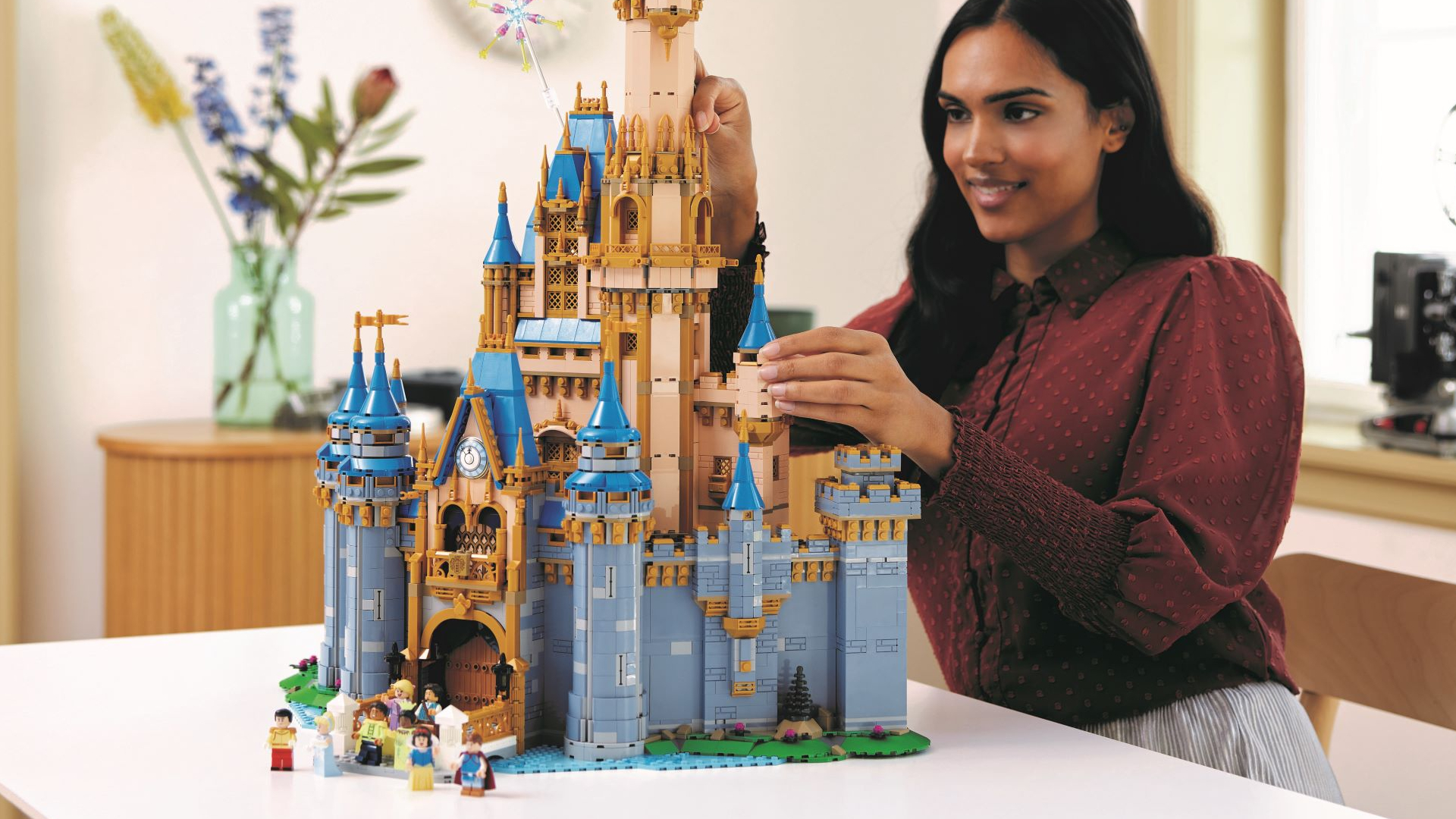 A woman places pieces on the Lego Disney Castle