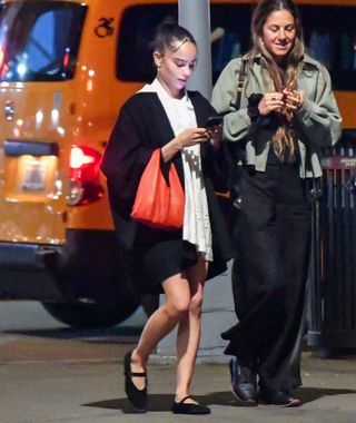 A photo of Zoë Kravitz wearing black Mary Janes and a small red bag