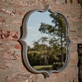 garden with quirky shaped mirror on stone wall