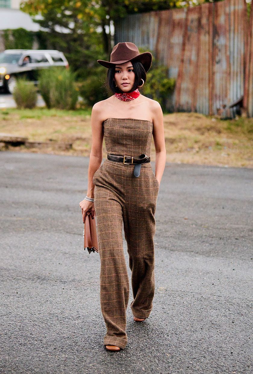 woman wearing brown cowboy hat with red bandana and one-piece jumpsuit