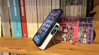 The Anker MagGo Power Bank (10K) connected to an iPhone 15 Pro on a wooden bookshelf