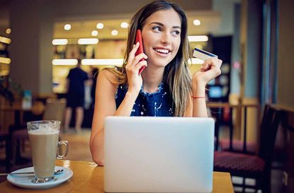 Young girl is sitting in a cafe, and shopping online using her credit card