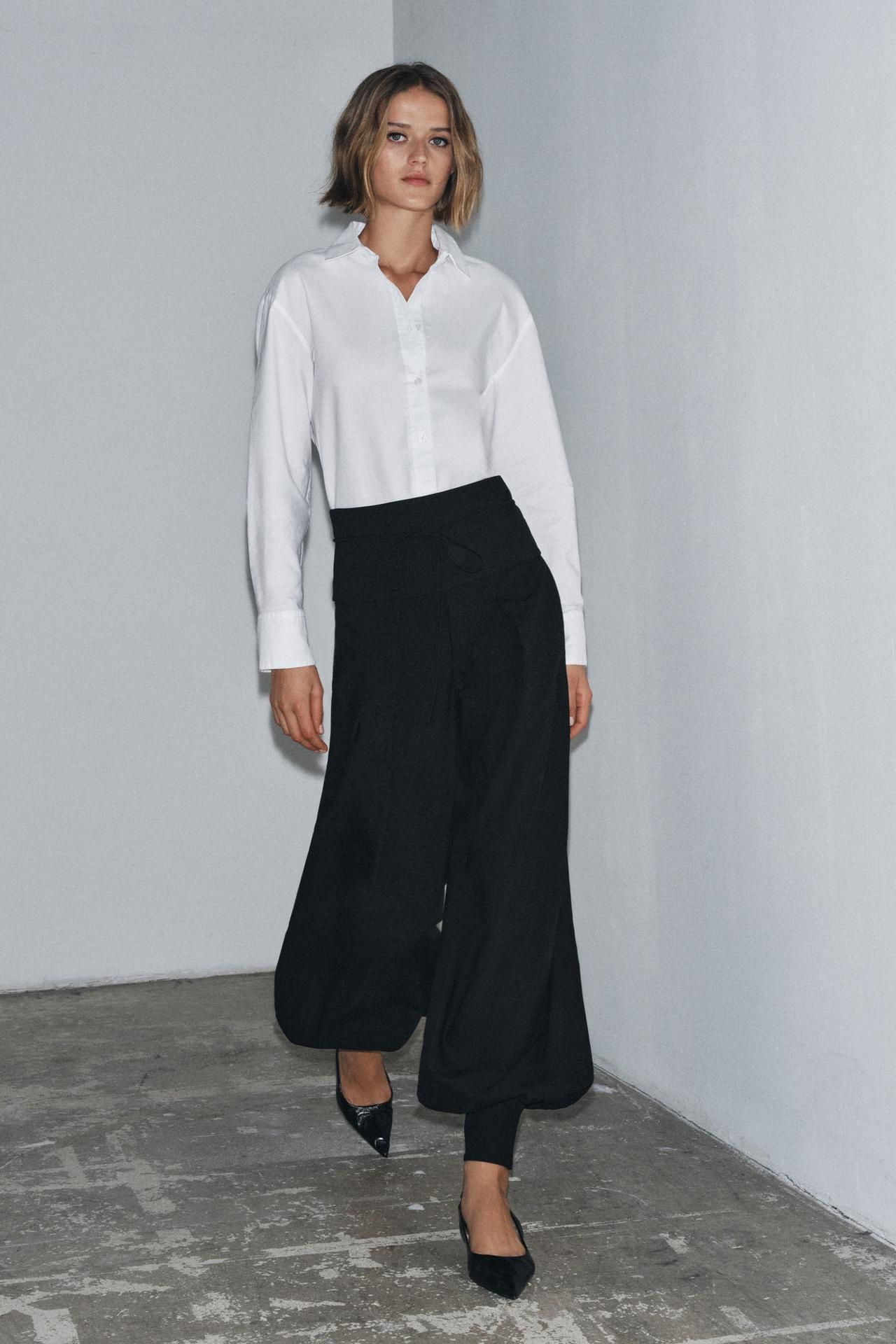 model wears white button down, black suited bloomers, and pointed toe sling back kitten heels