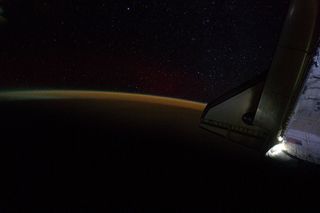 Earth's atmosphere and a starry sky just off the port wing of the docked space shuttle Endeavour are the subject of this image photographed by the Expedition 28 crew, while the shuttle was docked with space station on the STS-134 mission.