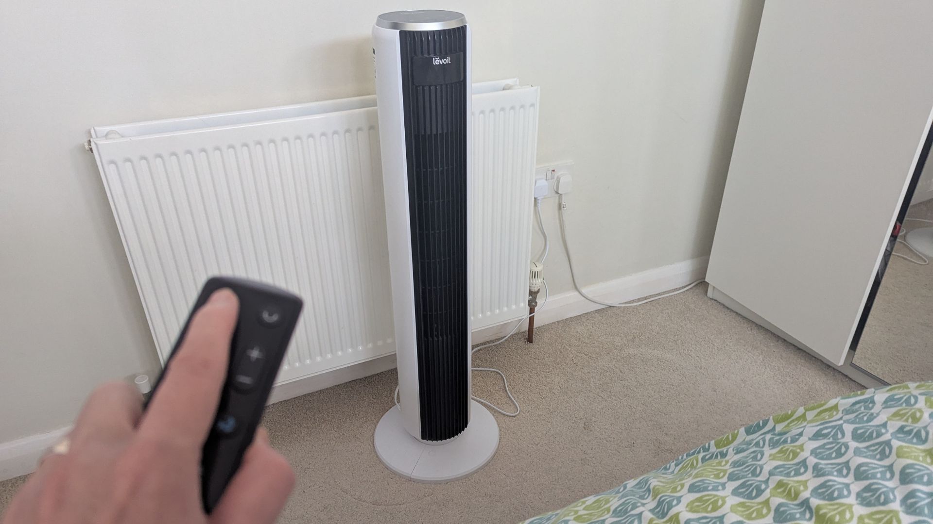 The remote being used with the Levoit Classic Tower Fan