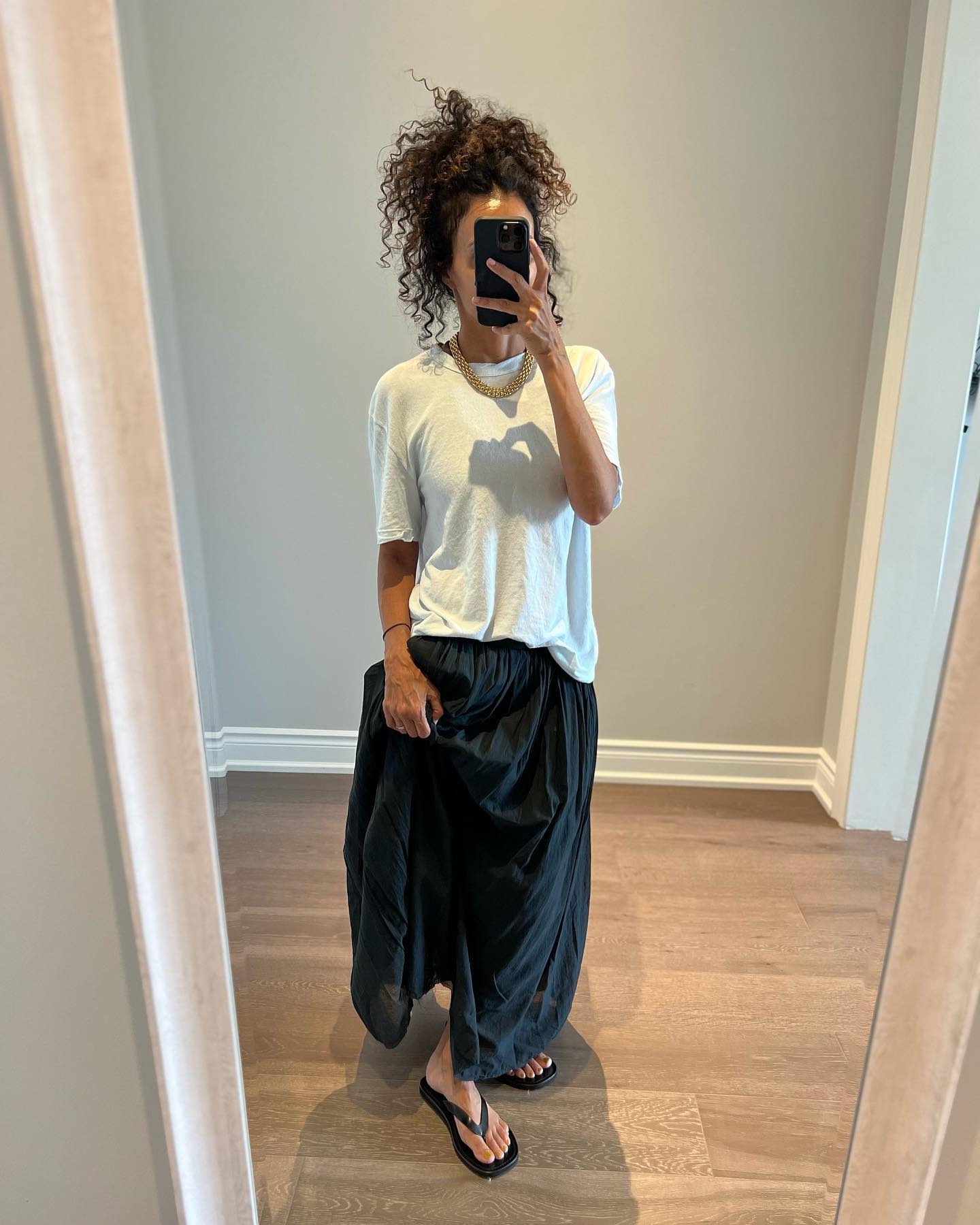 Woman wears white t-shirt, black skirt and black flip-flops
