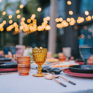 A beautifully adorned outdoor table, which has been tablescaped with gem-coloured glassware