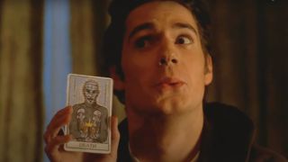 Henry Cavill mockingly holds a tarot card with Pinhead on it in Hellraiser: Hellworld.