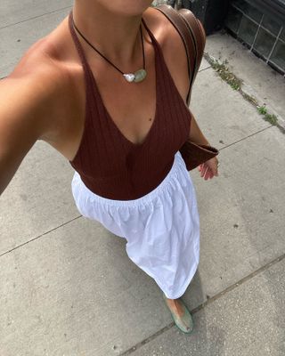 Woman in white skirt, top, and jelly shoes.