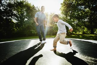 father and son running around on a trampoline - what to look for when buying a trampoline