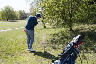 A golfer chipping out of the trees
