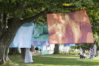 Self portraits printed on material hang from trees