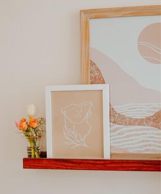 A wooden shelf with wall art and flowers on it