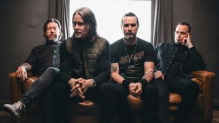 Alter Bridge sitting on a sofa in fronrt of a window