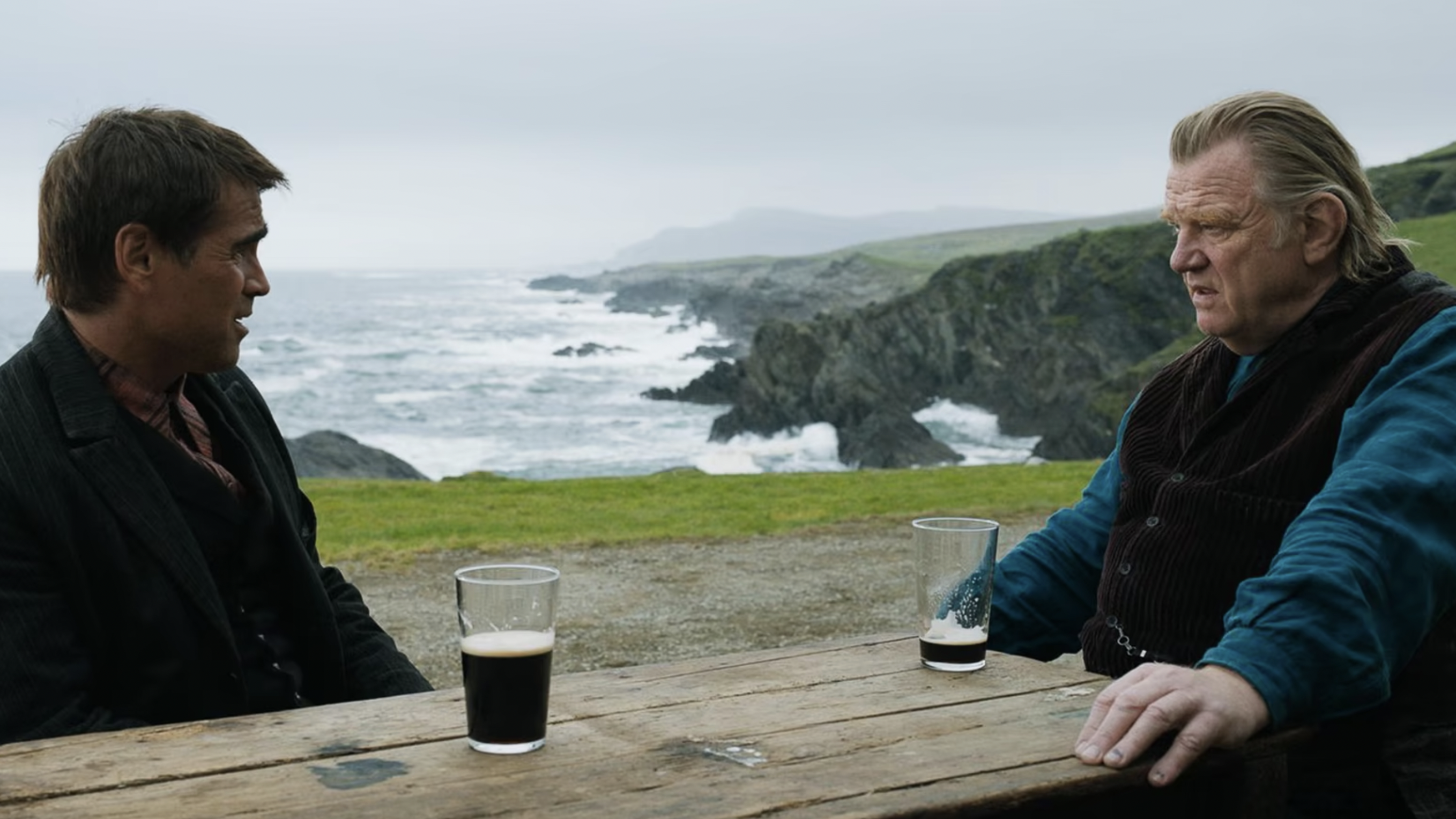 A still from the movie The Banshees of Inisherin in which Colin Farrell and Brendon Gleeson's characters are sat opposite each other at a table.