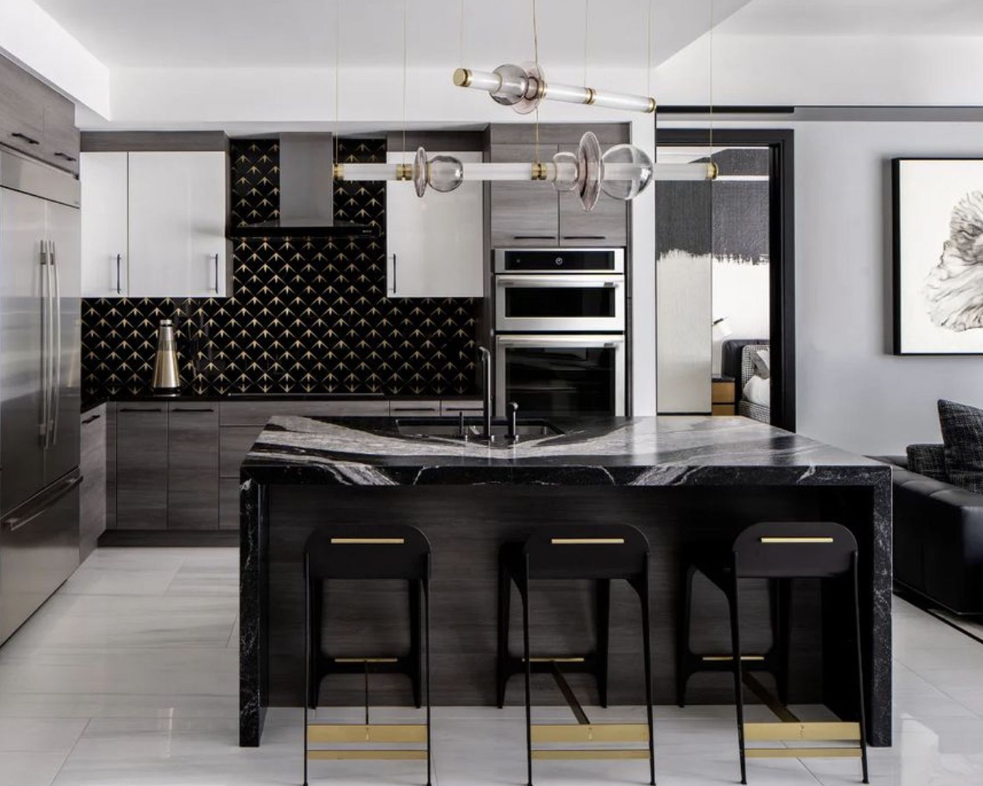 Modern, luxurious black kitchen with black marble island, black kitchen cabinetry, sculptural metal pendant light hanging over island