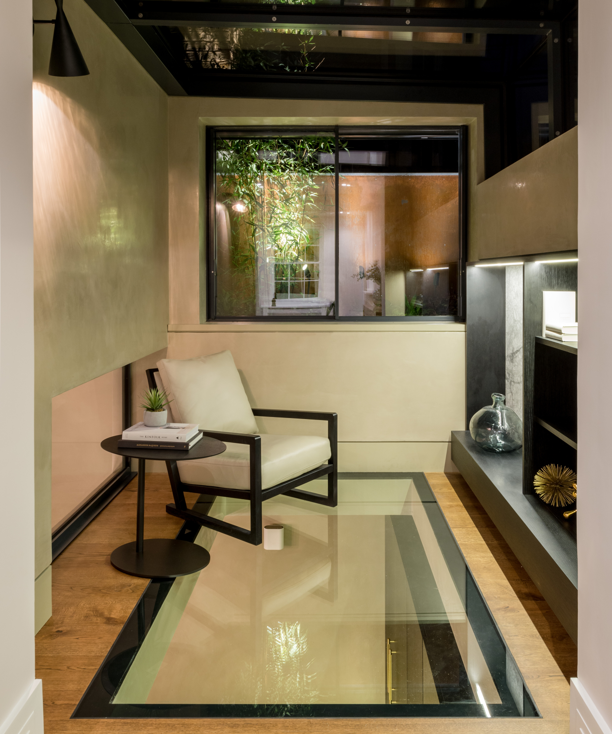 room with glass panel in wooden floor, armchair and TV