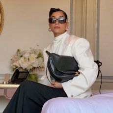 Tracee Ellis Ross wears red derby shoes with black trousers and a white high-neck blouse.