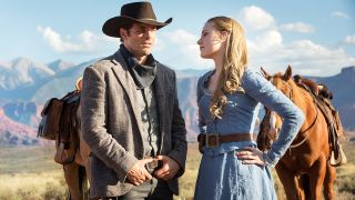 Två karaktärer från HBO Max-serien Westworld står ute på en slätt och kollar på varandra, med varsin häst bakom sig.