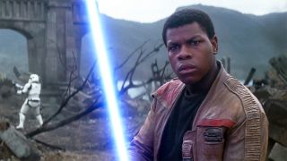 Finn looks confused as he wields a blue lightsaber in Star Wars: The Force Awakens