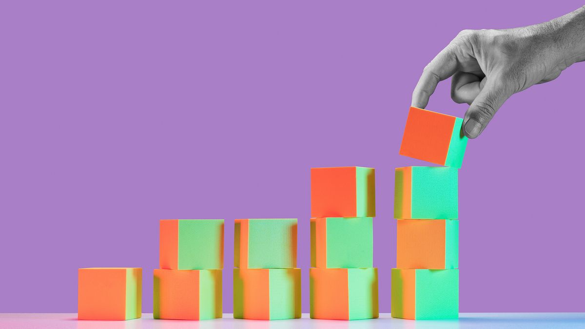 A vivid image of colourful blocks being stacked in five columns of one to four blocks high, with a black and white hand placing the fourth block on top of the far right column, indicating growth