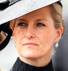 A headshot of Duchess Sophie wearing a black dress and huge black hat with diamond earrings at Royal Ascot 2014