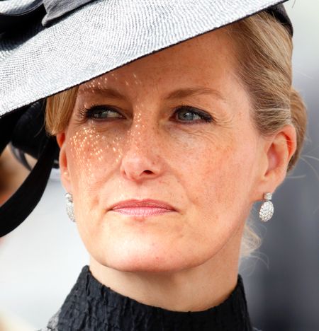 A headshot of Duchess Sophie wearing a black dress and huge black hat with diamond earrings at Royal Ascot 2014