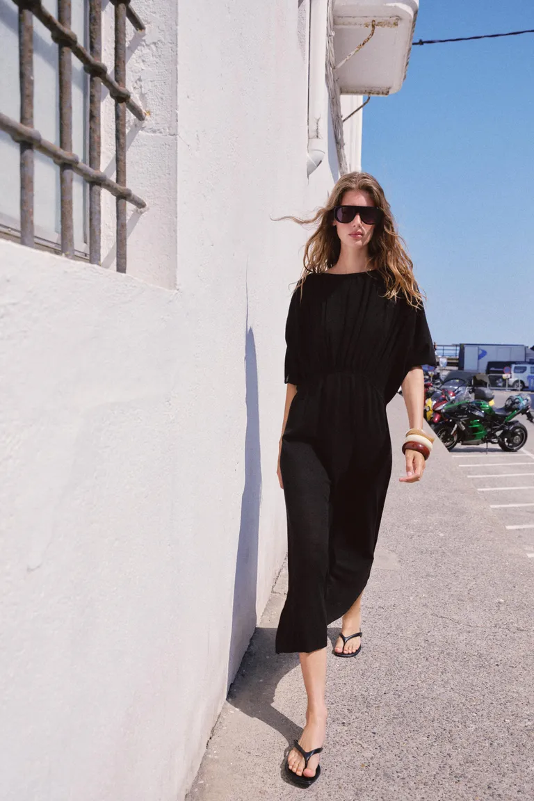 Woman wears a black dress, black sandals and colourful bangles