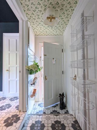 Entryway outside finished mudroom with hanging wall storage and black and white patterned floor tiles