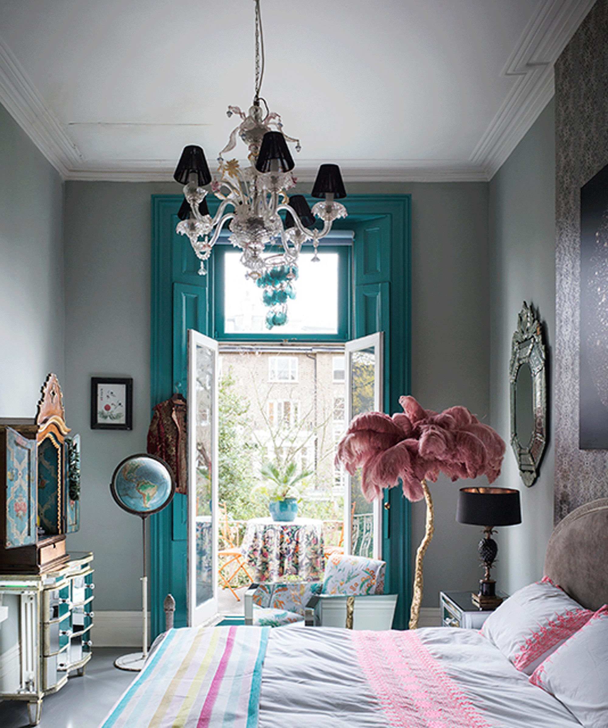 Maximalist bedroom with teal door and window frames leading to a balcony