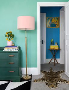painted green bedroom with dark green cabinet and pink lampshade