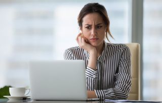 woman on laptop looking concerned