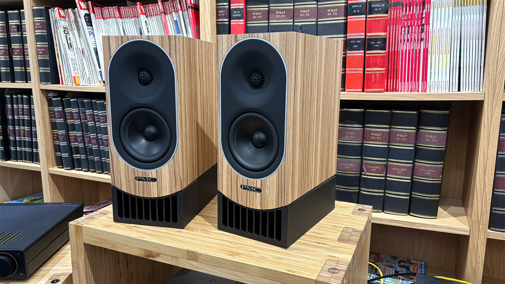 PMC Prophecy 1 standmount speakers on wooden hi-fi rack in front of bookcase