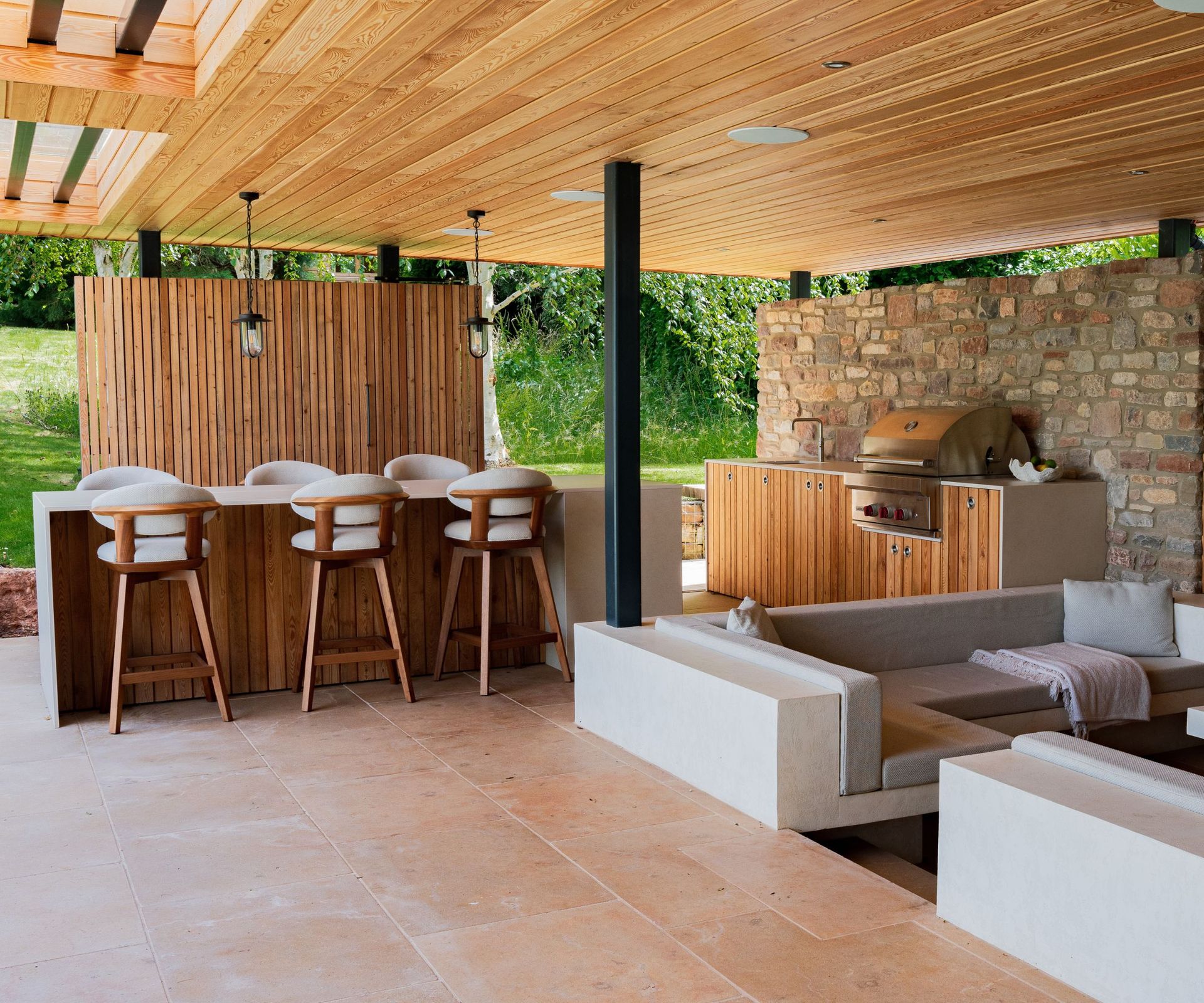 An outdoor kitchen with paneled walls, wooden cabinets, and a stainless steel cooker