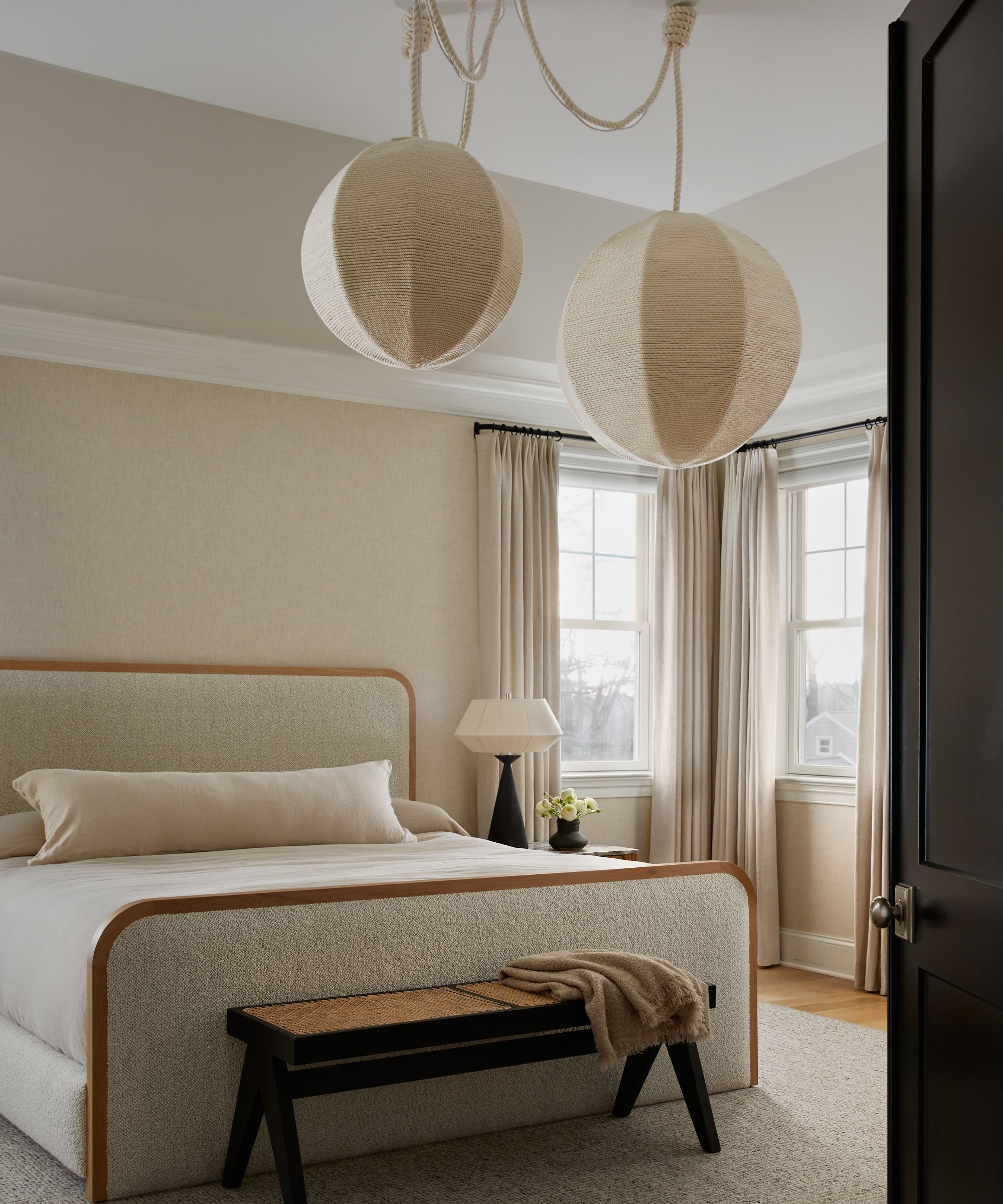 cream bedroom with big pendant light and corner window