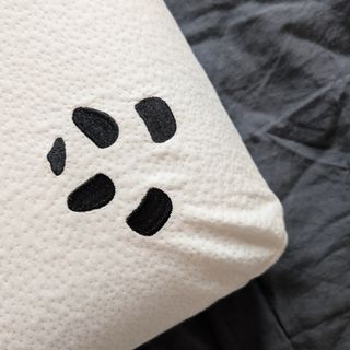 The Panda Memory Foam Bamboo pillow being tested on a grey linen duvet cover