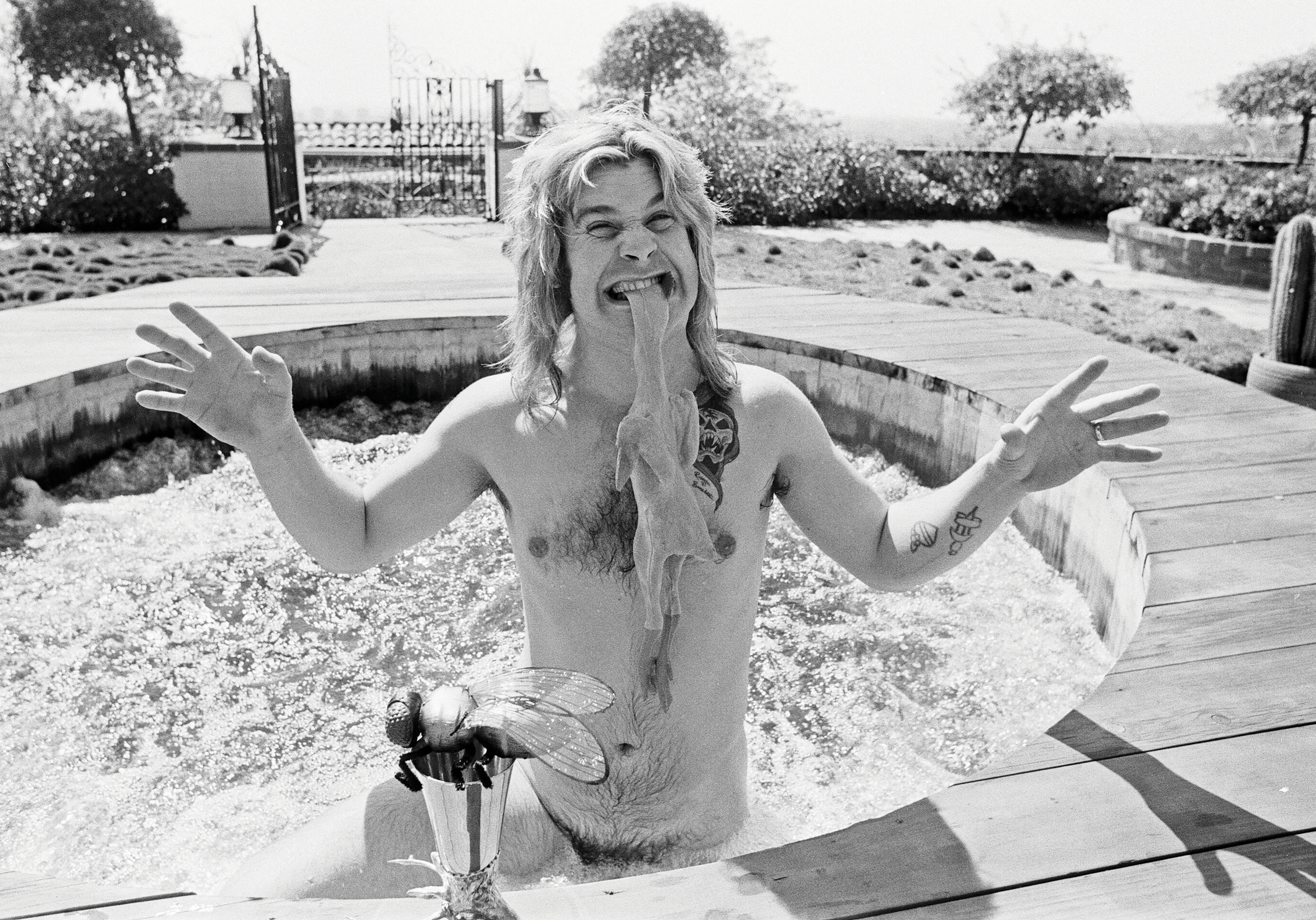 Ozzy Osbourne in a hot tub with a rubber chicken in his mouth