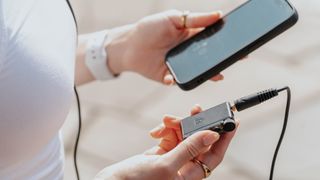 Lifestyle shots showing a model's hands holding the iFi GO Blu Air portable DAC