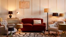 red sofa in wall panelled room surrounded by lamps