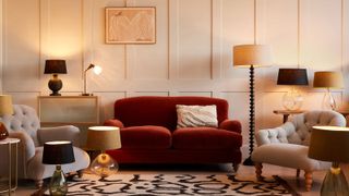 red sofa in wall panelled room surrounded by lamps