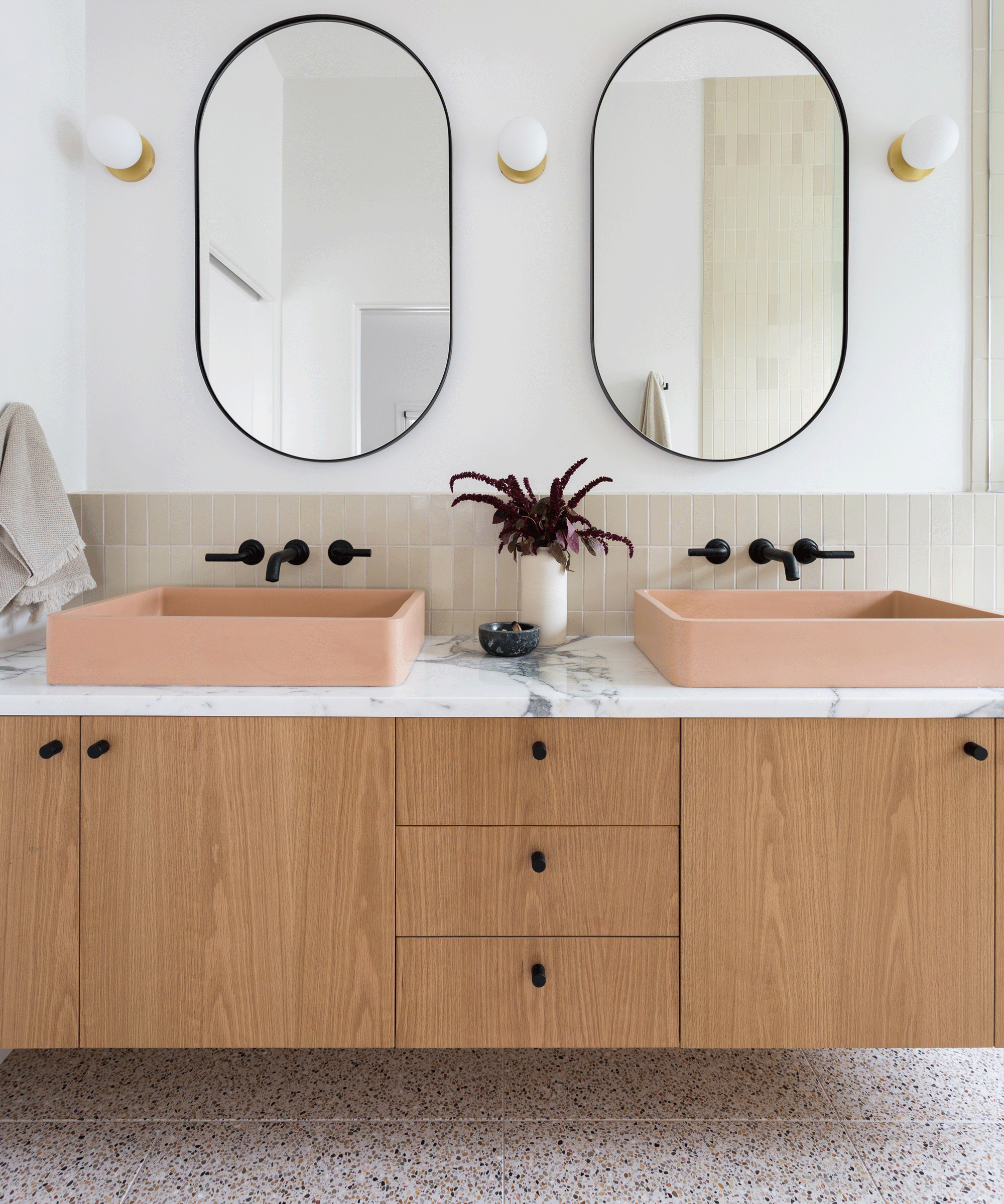 bathroom with double pink sink and oval mirrors on wood vanity